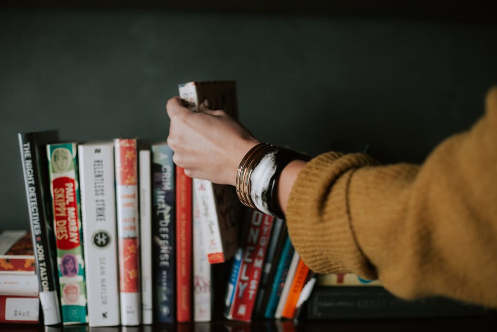 a womans hand placing a book back on the shelf after book club team building with her small business colleagues