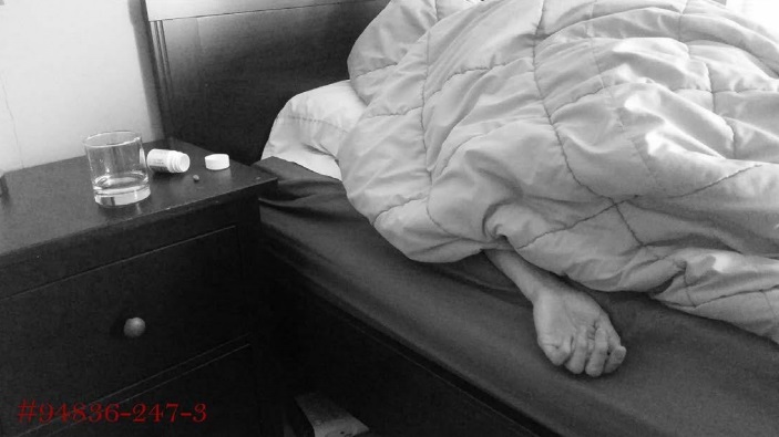 A person laying under a blanket, with only their hand visible