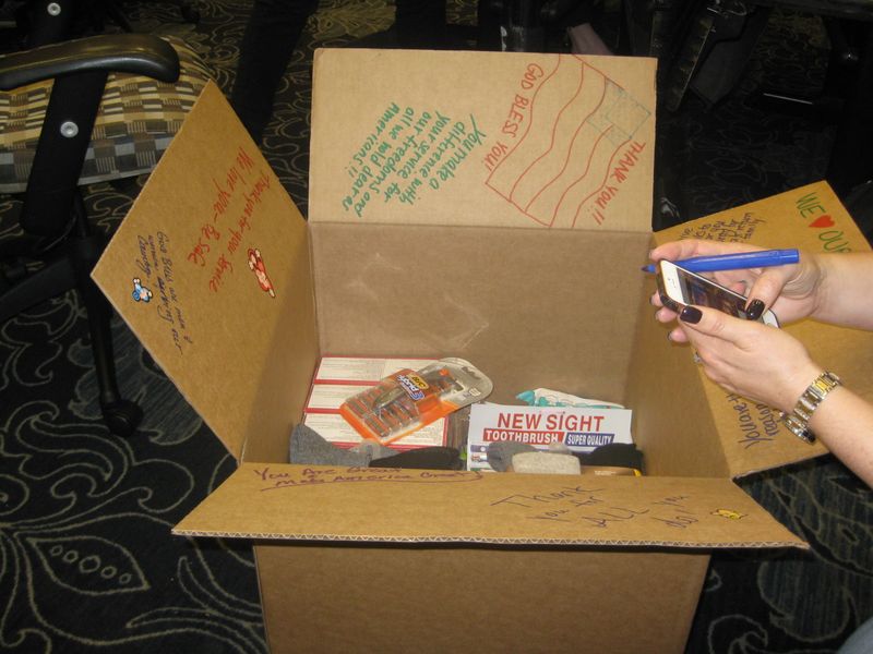 a workgroup assembling a gift box to be sent to those in need with a philanthropic team building activity