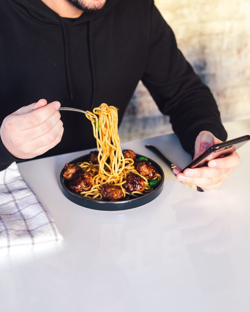 Food-related ice breaker question ideas section image with guy eating spaghetti and meat balls