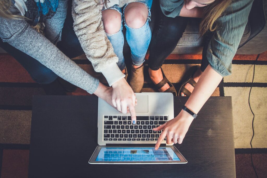 three teammates collaboratively solving a problem together while looking at a laptop on a desk